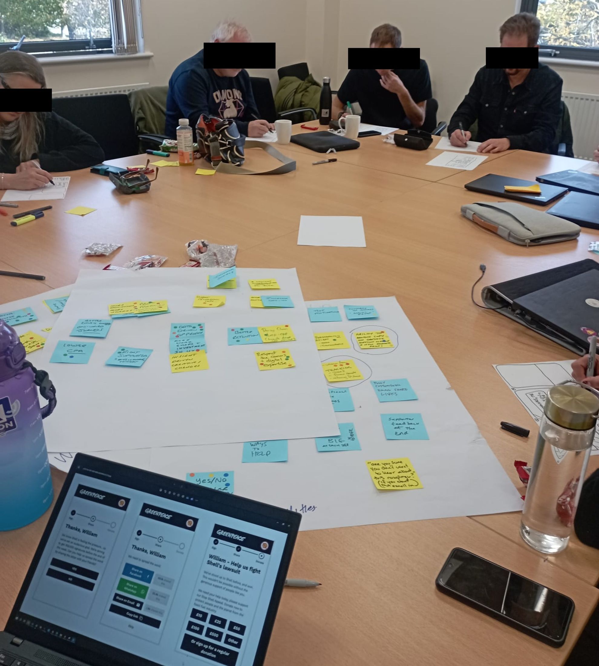A co-design workshop session, sorting sticky notes into themes around a table while reviewing a prototype